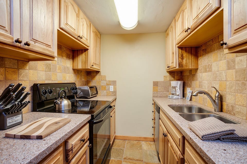 Cook your favorite meals in this fully equipped galley kitchen featuring granite counters, maple cabinetry, and everything you need for home cooking.