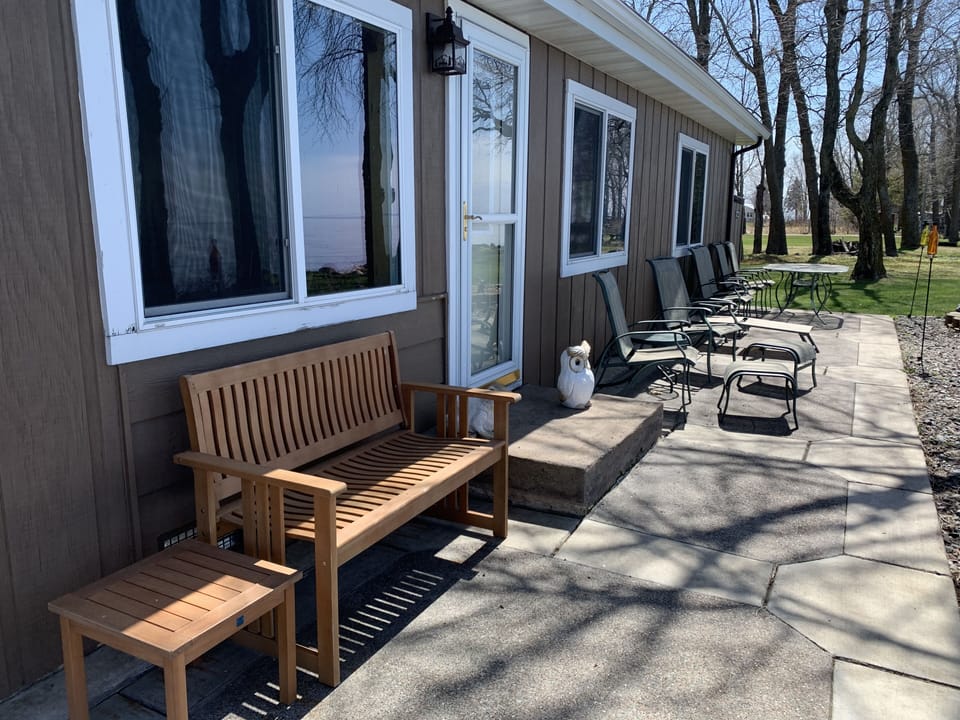 Lakeside patio with dining table, 6 chairs, a bench and lounge chair 
