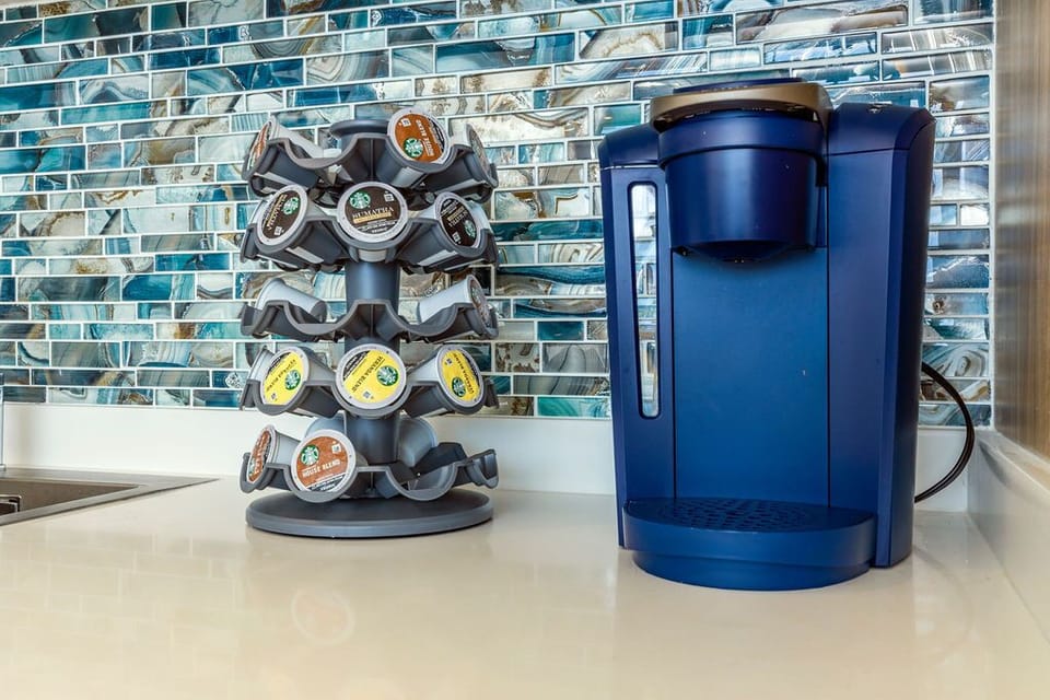 Start your mornings right with your own coffee maker and pods, set against stunning turquoise tile—your perfect home away from home.