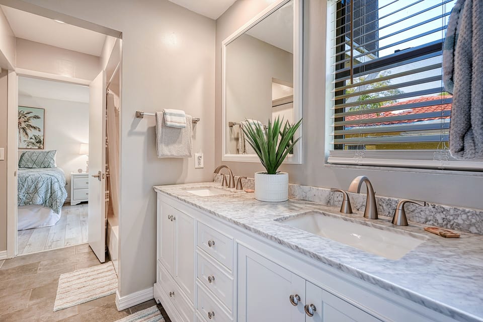 Bathroom with double vanity, marble countertop, and window