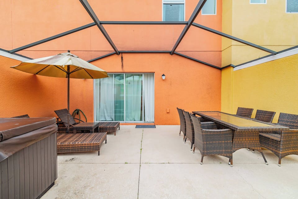Step outside to a vibrant patio, where warm orange walls create a cheerful atmosphere. Relax on the comfortable lounge chairs or gather around the spacious dining table, perfect for al fresco meals amidst the sun and shade.