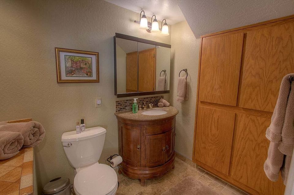 Bathroom with a rounded vanity and a tall cabinet.