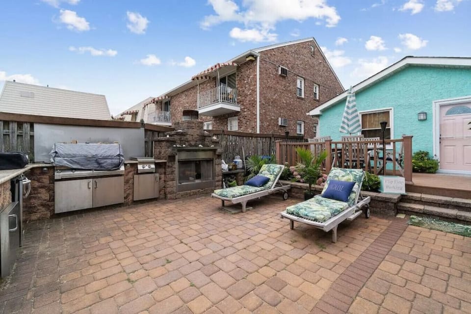 Spacious backyard featuring lounge chairs, built-in grill, and cozy fireplace