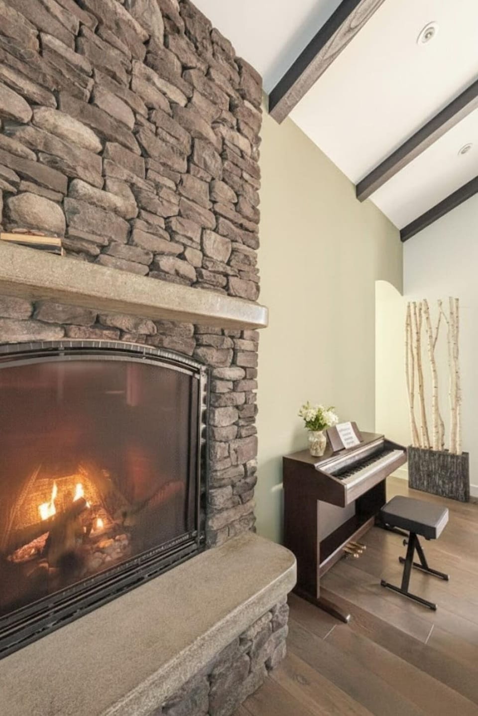Cozy living room with warm stone fireplace and piano ambiance