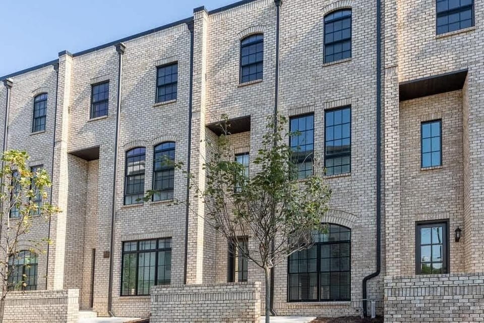 Modern brick townhome complex with elegant architecture, oversized windows, and a beautifully designed community atmosphere.