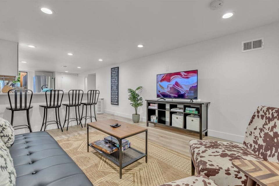 Bright open living room with TV, cozy seating, and breakfast bar