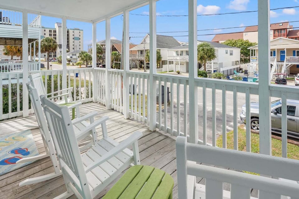 Covered porch with white rocking chairs and a neighborhood view at Sea Lakes 103C, Cherry Grove