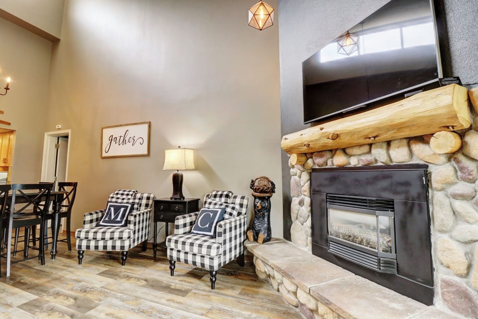 Cozy fireplace and seating in the living room. A large TV is mounted above the fireplace.