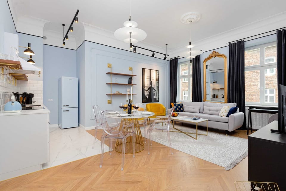 Elegant living room with a fold-out sofa bed, TV and kitchenette with dining area.