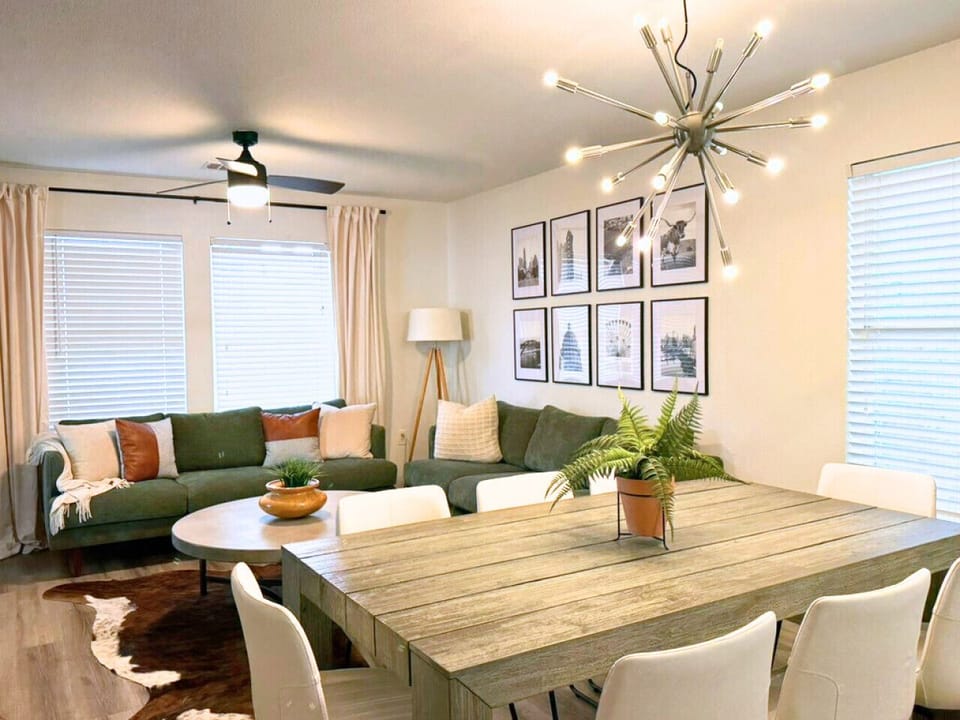 Bright, open living and dining space with modern lighting, cozy sectional, and local art—ideal for relaxing after exploring downtown Austin.