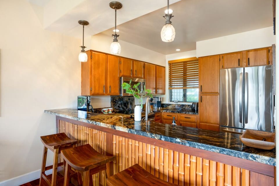 Bar height counter with barstools, granite counters, stainless appliances.