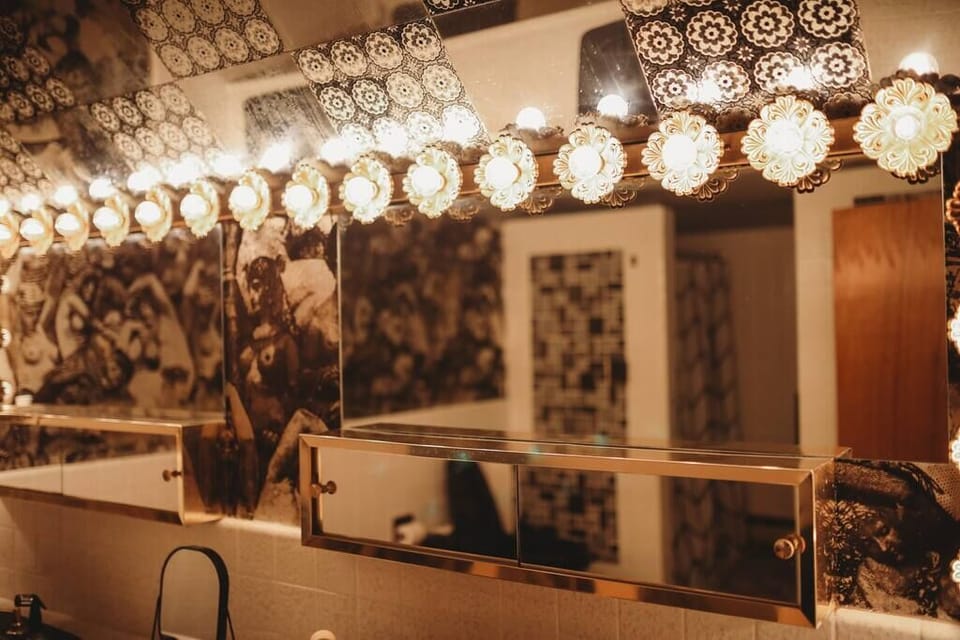 Bathroom on the main floor attached to the main bedroom, featuring stylish vintage wallpaper and an elegant vanity with bright lighting.