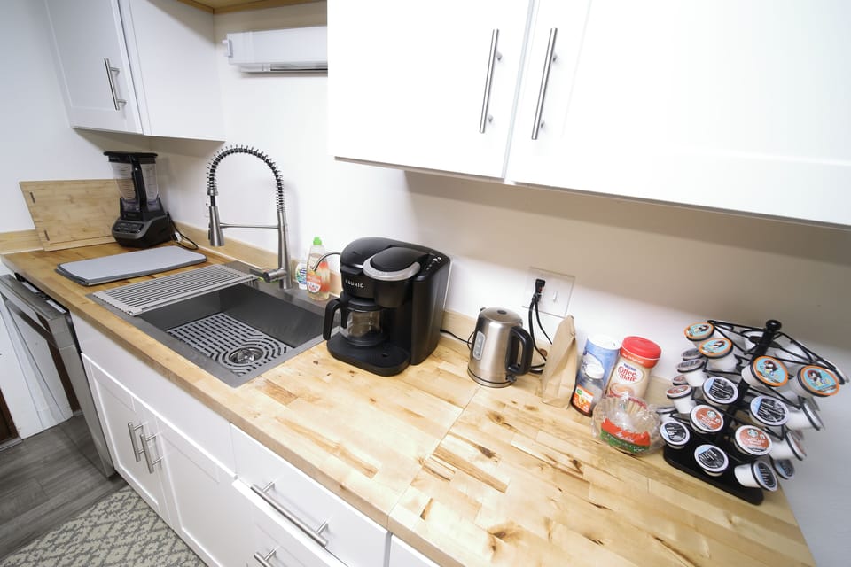 Modern kitchen with sleek white cabinetry, a functional sink, and a coffee station for convenient brewing.