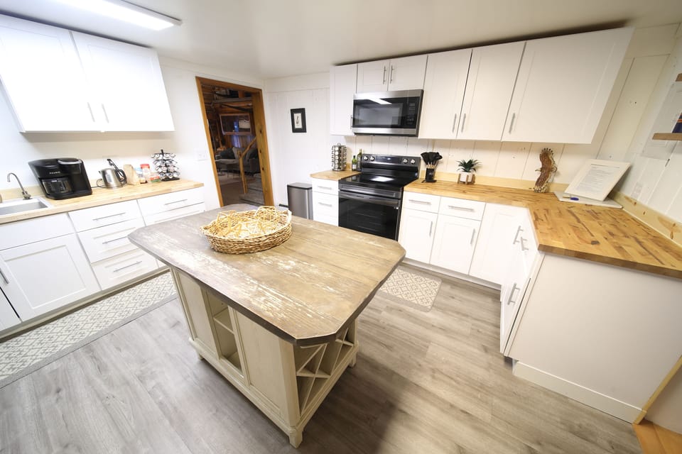 Open and inviting kitchen layout featuring clean white cabinetry, wooden countertops, and a spacious central island.