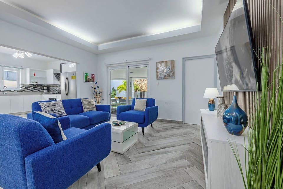 Step into effortless relaxation. From the sleek chevron floors to the vibrant pops of blue, this living room is designed for ultimate comfort.