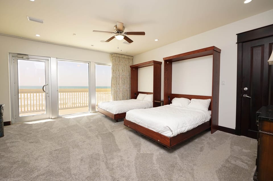 Wake up to stunning gulf views in this spacious bedroom featuring two comfortable Murphy beds and direct beach access.