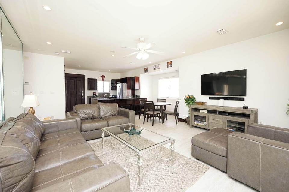 Relax in your spacious open-concept living area with plush leather seating, modern entertainment center, and seamlessly connected kitchen for effortless vacation living.