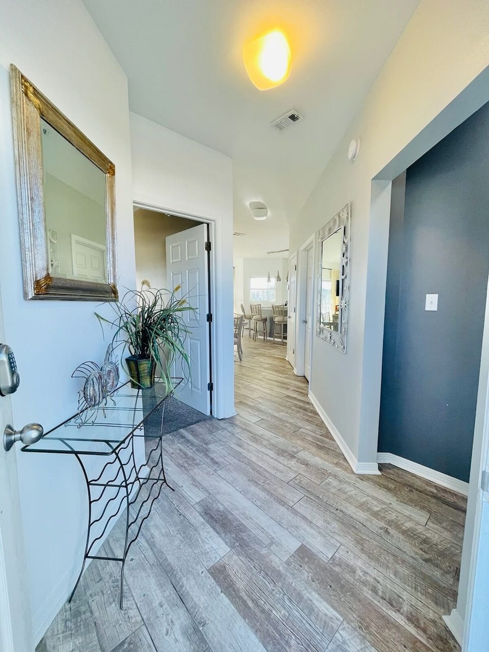 Step into your stylish hallway featuring elegant wood-look flooring and a thoughtful glass accent table with fresh greenery to welcome you home.