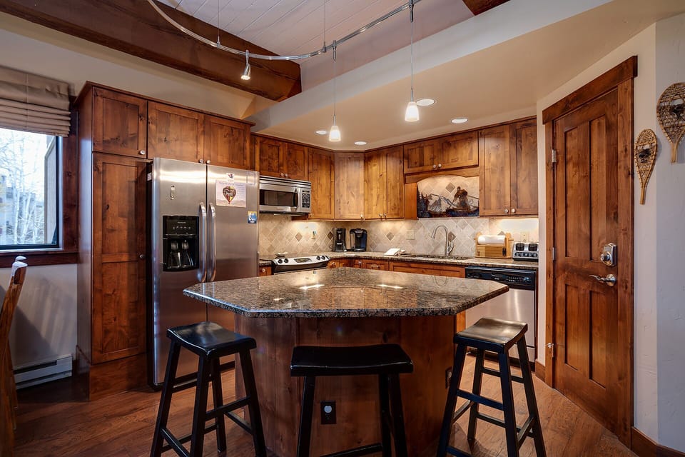 Gather around your fully-equipped kitchen island where rustic wood cabinets and granite counters create the perfect space for morning coffee and meal prep.