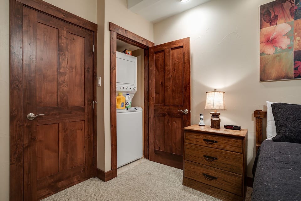 Your cozy bedroom features convenient in-room laundry facilities and rich wooden furnishings that create a warm, mountain retreat atmosphere.
