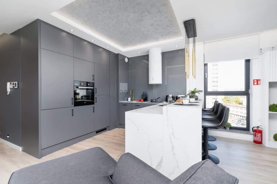 A functional kitchenette with a countertop at which bar chairs stand.