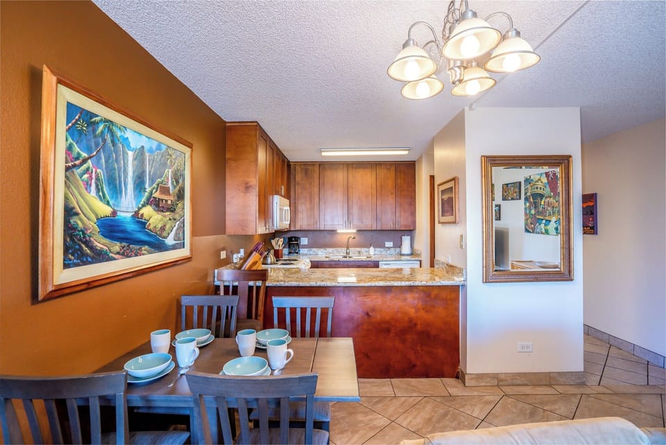 Gather around this inviting dining and kitchen space, where warm wood cabinetry, granite counters, and vibrant artwork create a cozy atmosphere for your meals and memorable moments together.