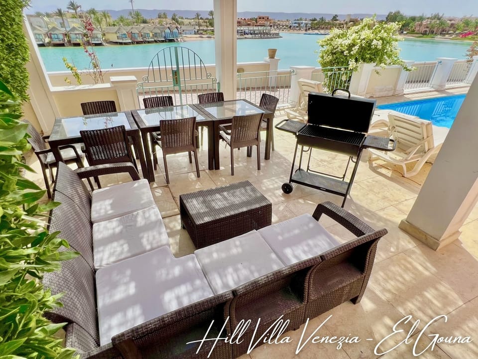 Outdoor seating and lounge area with a BBQ and sun loungers by the pool.