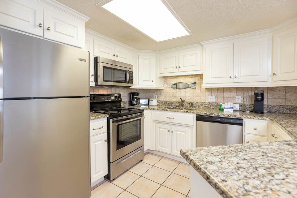 The kitchen features granite countertops, stainless appliances, Keurig, coffee maker, and charming fish decor