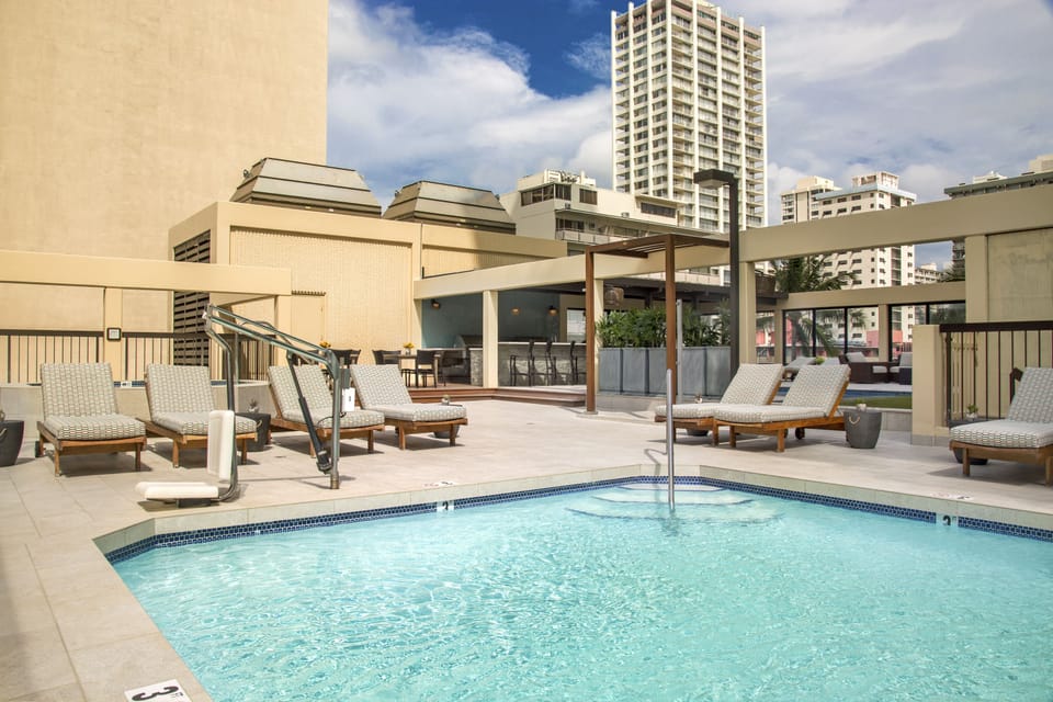 Soak up the sun by the sparkling pool, where plush loungers invite you to relax on the expansive deck overlooking the city skyline.