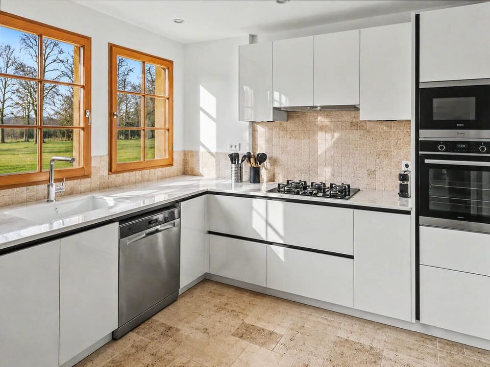 Bright kitchen with modern equipment and open view of greenery.