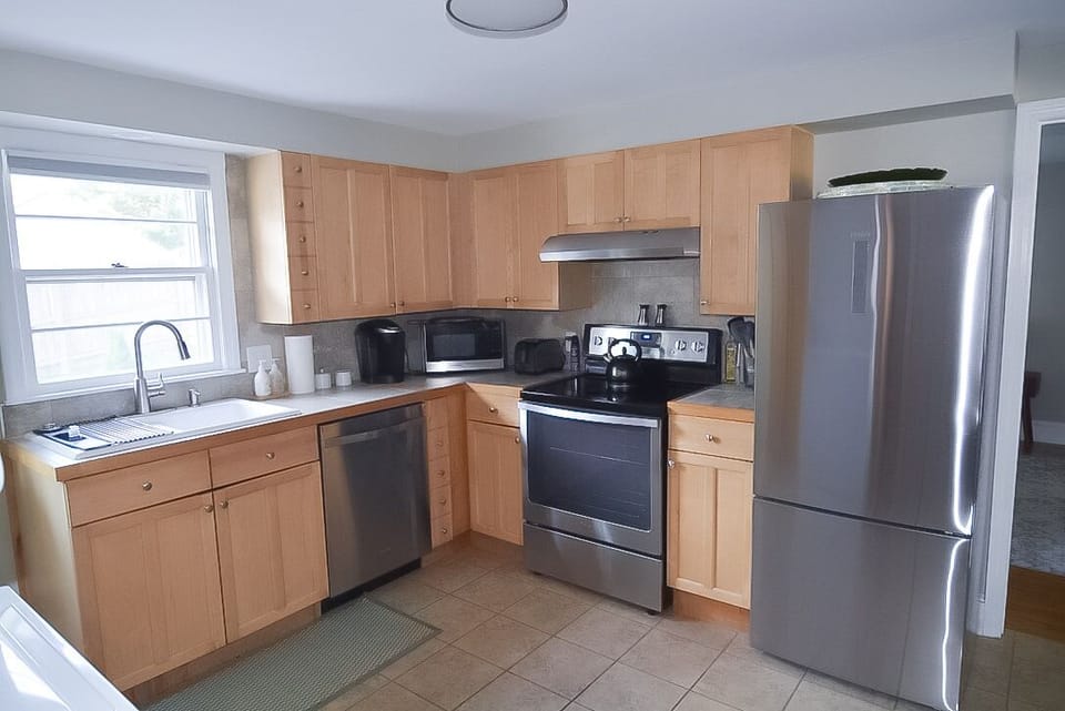 Fully equipped kitchen with full sized glass top electric range and refrigerator