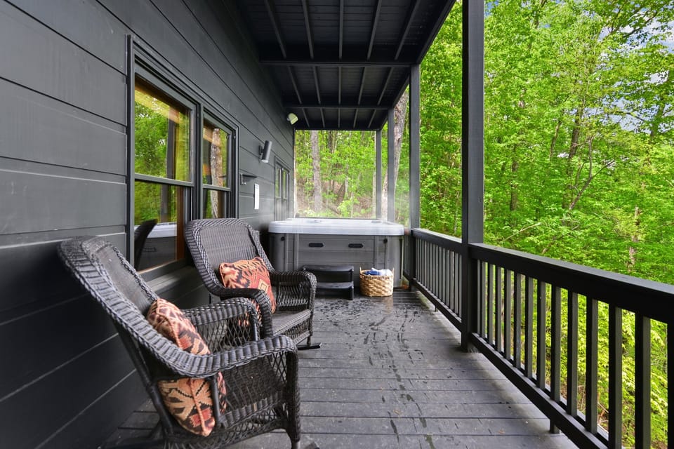 Claim the porch hot tub tucked beside cushioned wicker chairs, where lush hillsides frame every soak and rain never interrupts your evening.