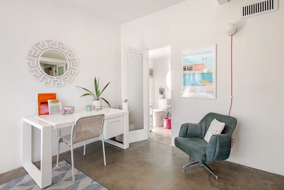 Sunlit style for work or play ✨💻🪞 With a modern desk and mirror framed by natural light, this bright room is made for both focus and flair. #DesertLight #PalmSpringsLiving #AirbnbFind