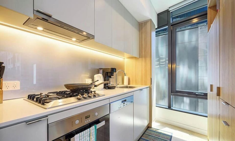 Modern kitchen with gas cooktop, oven, dishwasher, and balcony access.