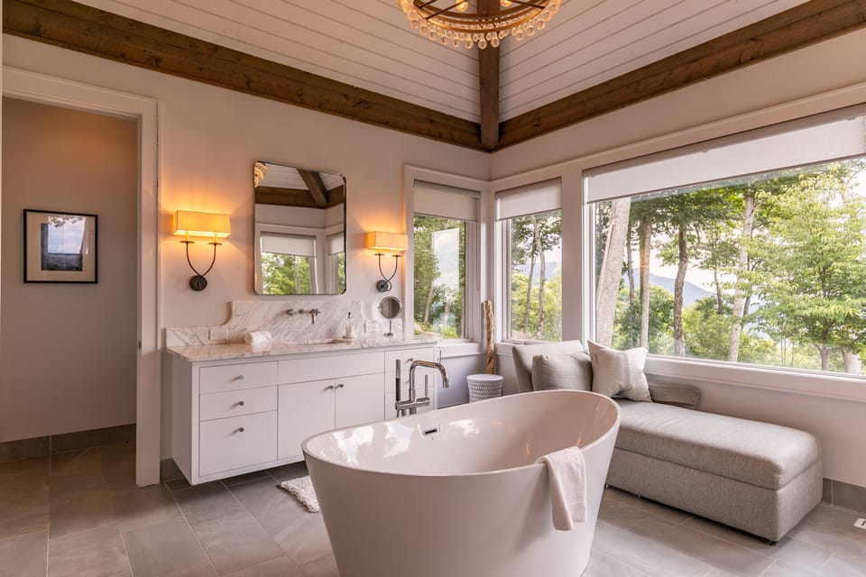 Soak it all in. A freestanding tub, warm sconce lighting, and treetop mountain views make this bath feel like a private spa.