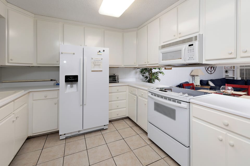 White kitchen with white appliances and tile floor