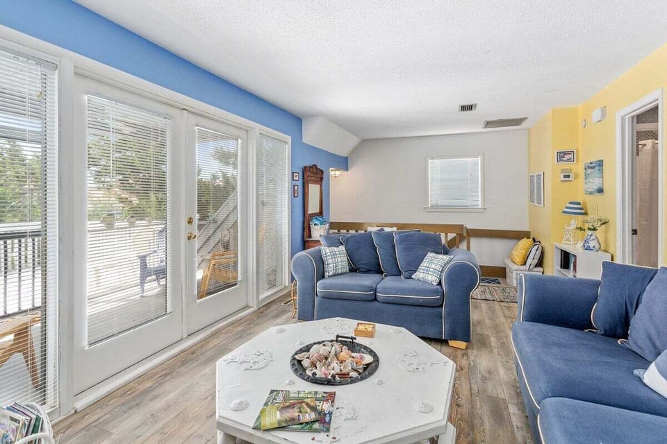 Living room with blue sofas, sliding doors, and yellow accent wall