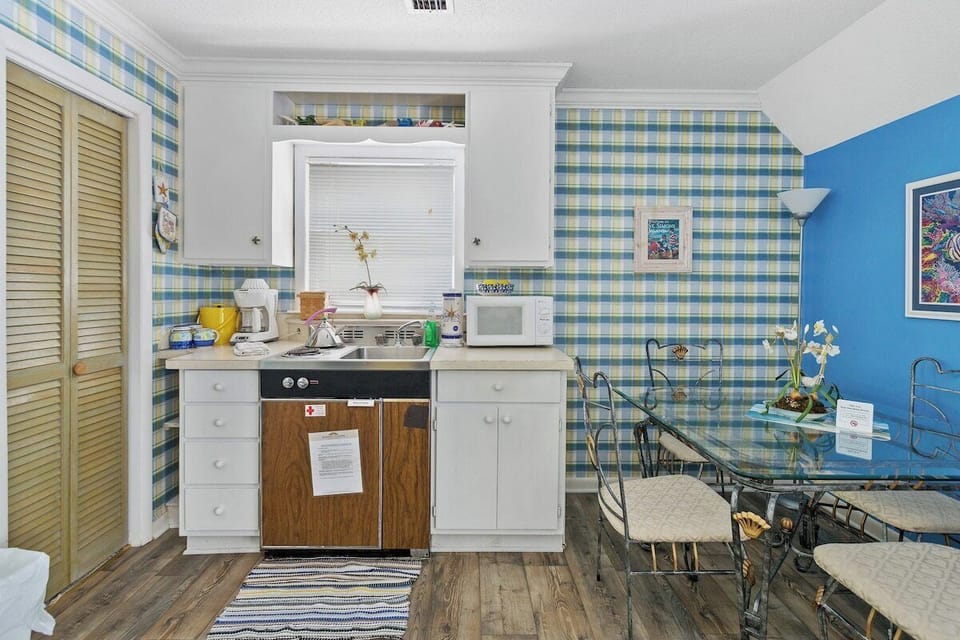 Kitchenette with white cabinets, plaid wallpaper, and dining table