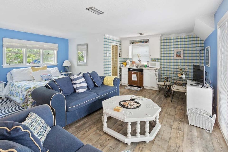 Open living and sleeping area with blue sofas and flat-screen TV