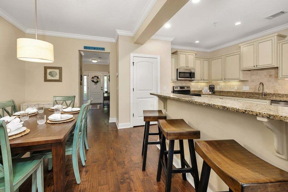 Dining area with wood table, teal chairs, bench, and kitchen beyond