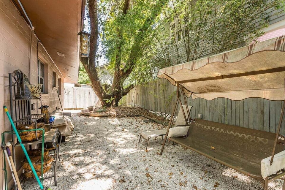 Side yard with swing, fence, and tree canopy overhead