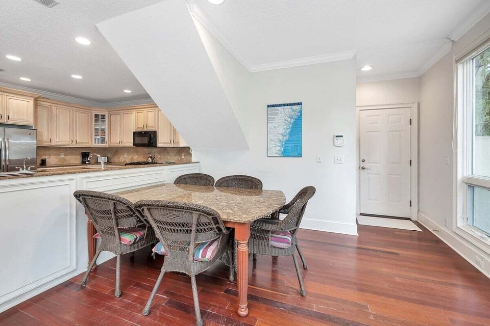 Open dining area with rattan chairs adjacent to kitchen