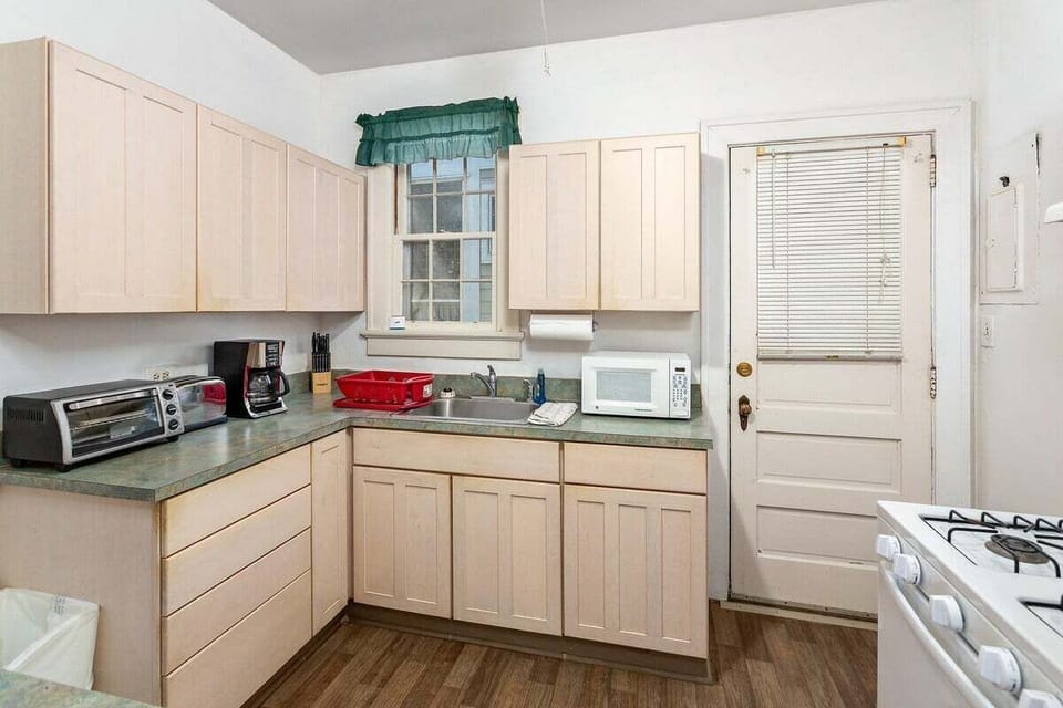 Light wood kitchen with white appliances and garden window