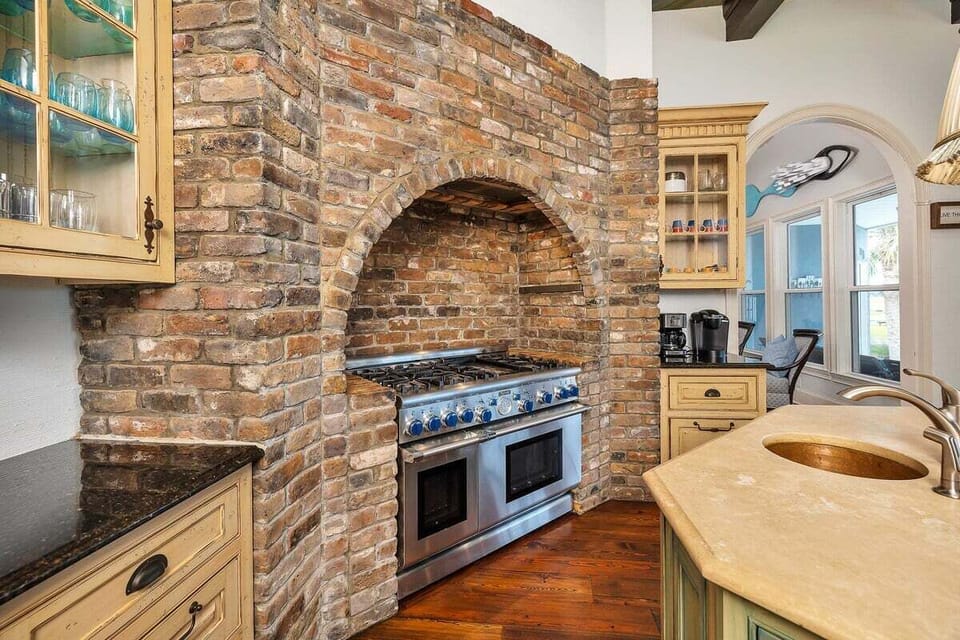 Stainless steel stove inside a rustic brick arched kitchen alcove