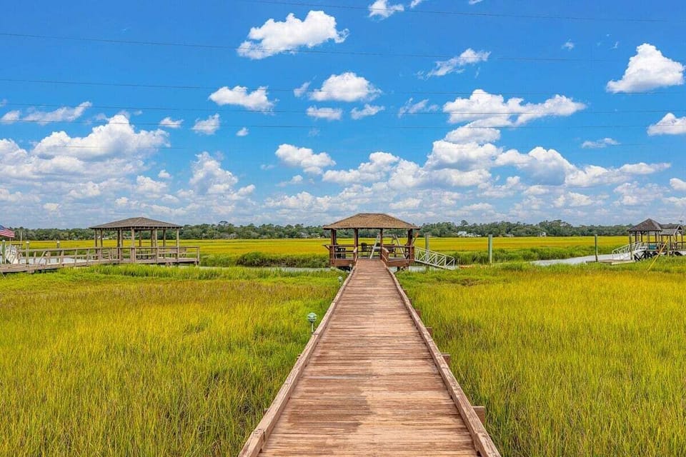 Property's wooden boardwalk and dock surrounded by marsh