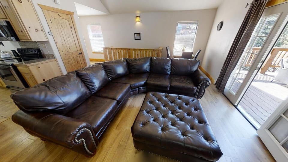 Sink into rich leather seating in your open-concept living space, where natural light pours through multiple windows and a walkout balcony invites fresh mountain air.