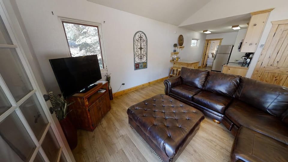 Sink into the rich leather sofa and unwind in your light-filled living room, where rustic wood accents and mountain views through the window create a cozy retreat perfect for relaxation.
