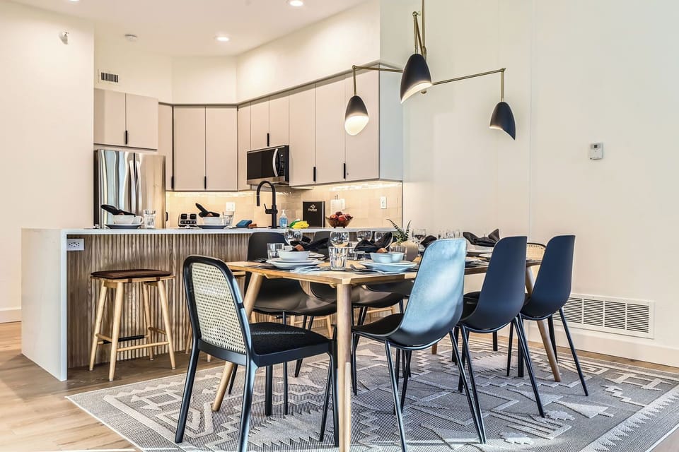 Enjoy meals under a stylish light fixture in this open dining space. It flows into a cozy living room with a stone fireplace, perfect for your mountain getaway.