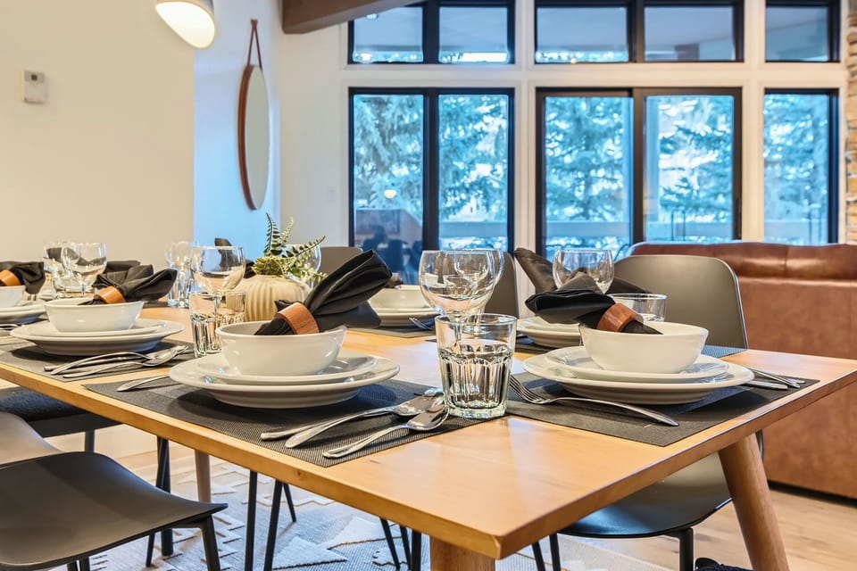 Enjoy meals under a stylish light fixture in this open dining space. It flows into a cozy living room with a stone fireplace, perfect for your mountain getaway.