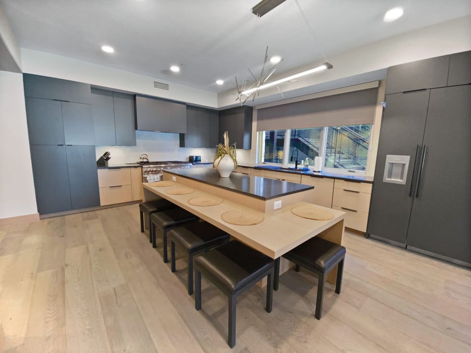 Prepare meals in our fully equipped kitchen, featuring a large island with bar seating, modern stainless steel appliances, and stylish wood accents. All the essentials for a great stay.